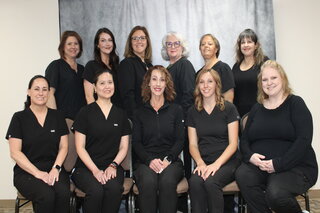 Several female hospital staff members sitting next to each other, smiling.
